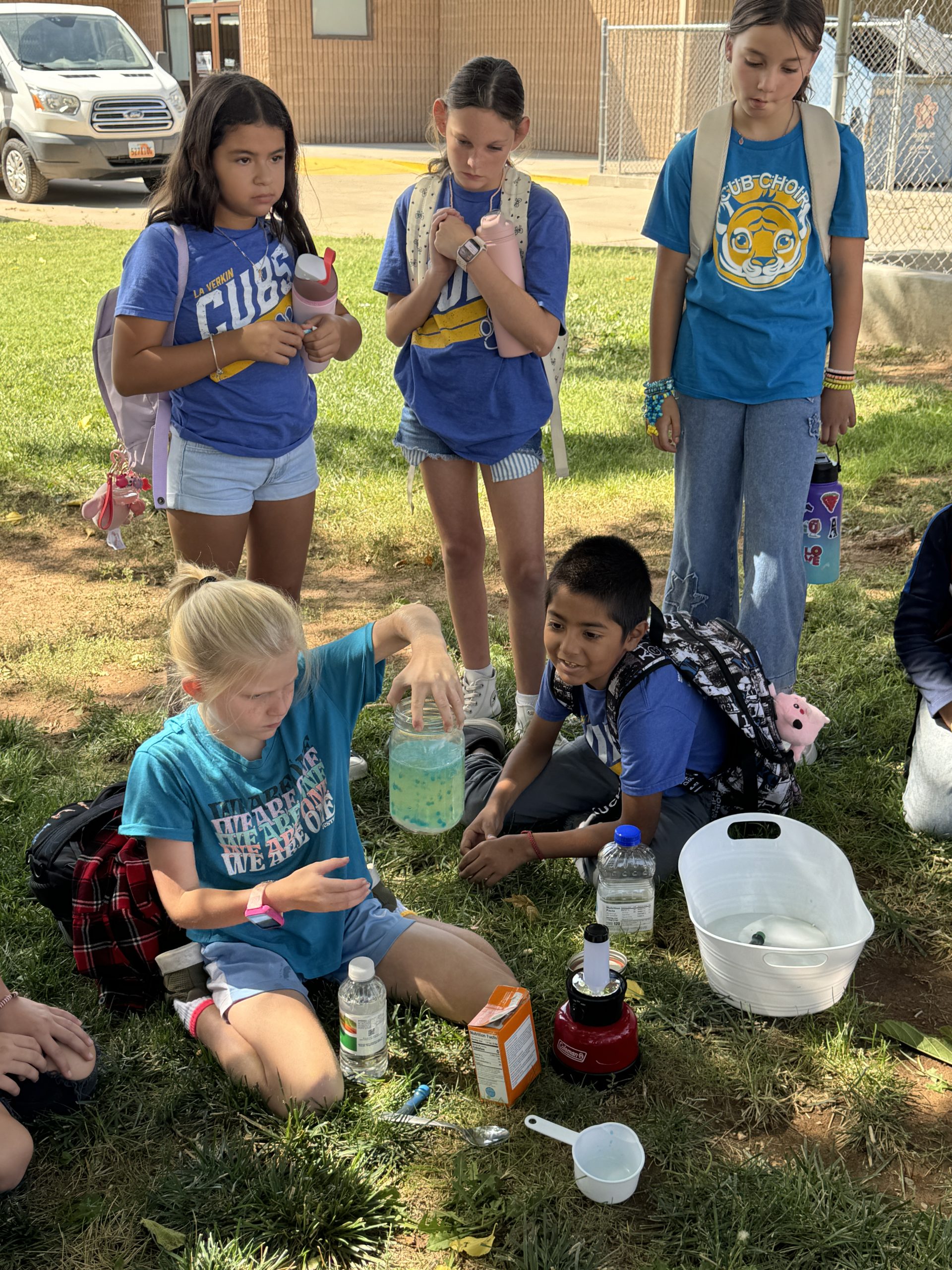 Group of students outside in the grass doing a science project