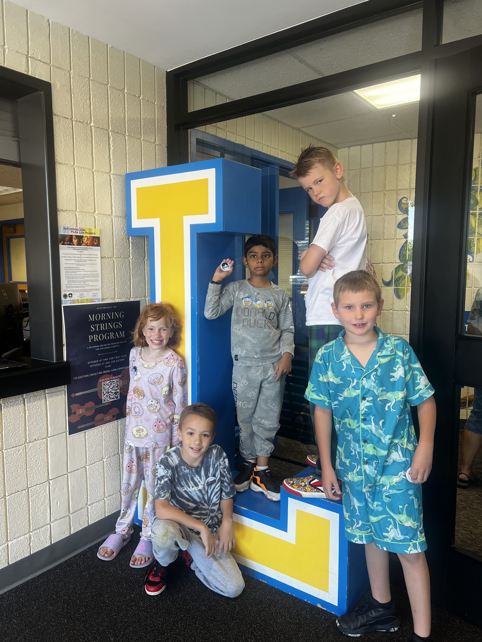 Group of students standing on or near the blue and yellow L at the front of the school.